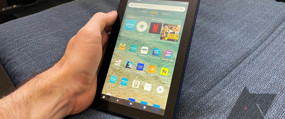 A person is holding a black tablet with their left hand