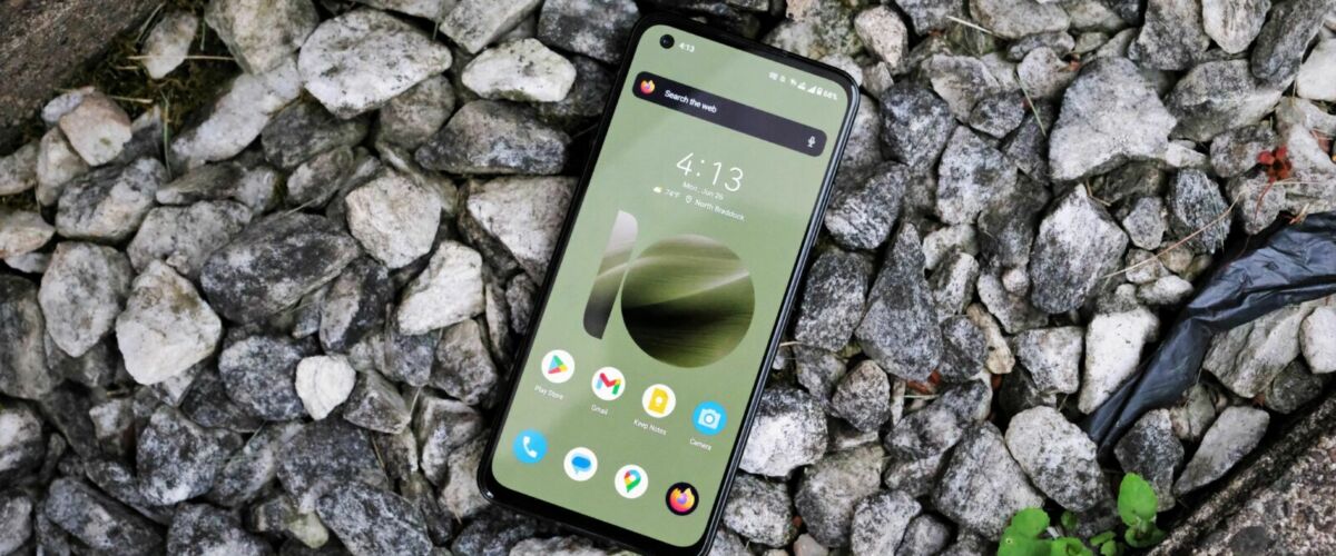 A smartphone with a green display rests on rocks.