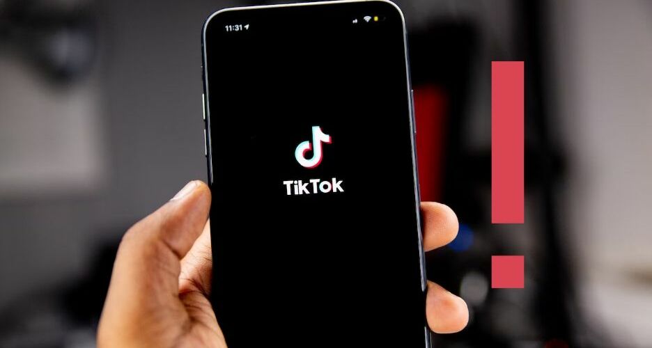 Person holding a phone with the TikTok logo on the screen