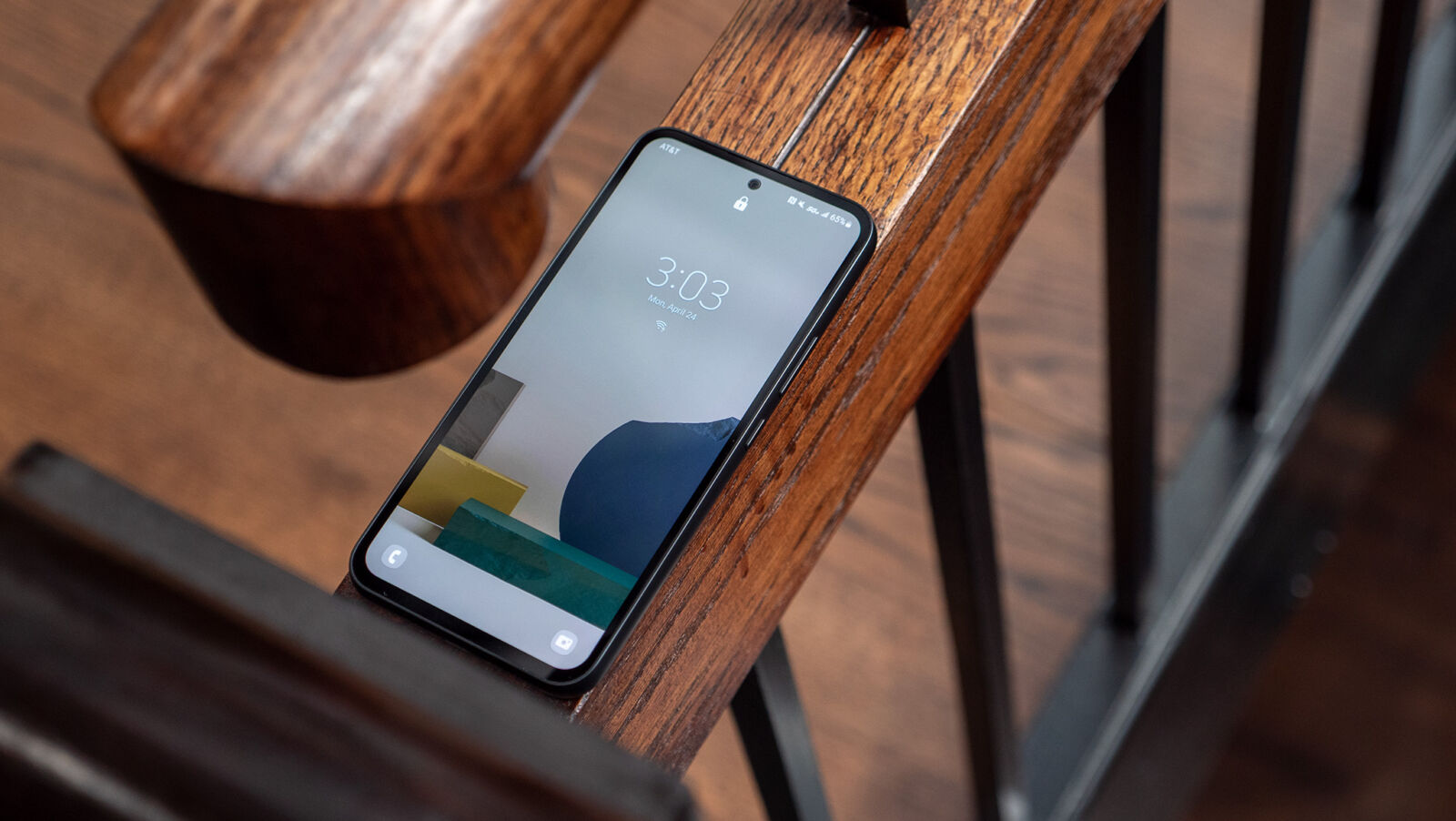 The Samsung Galaxy A54 5G sitting on a stair rail showing its lockscreen