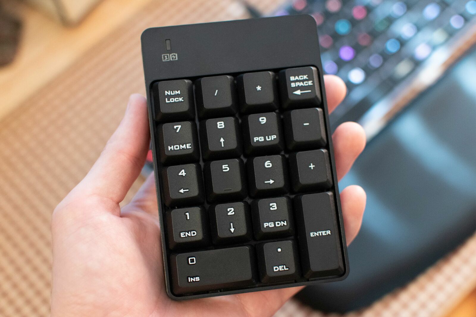 A hand holding a standalone wireless numpad.