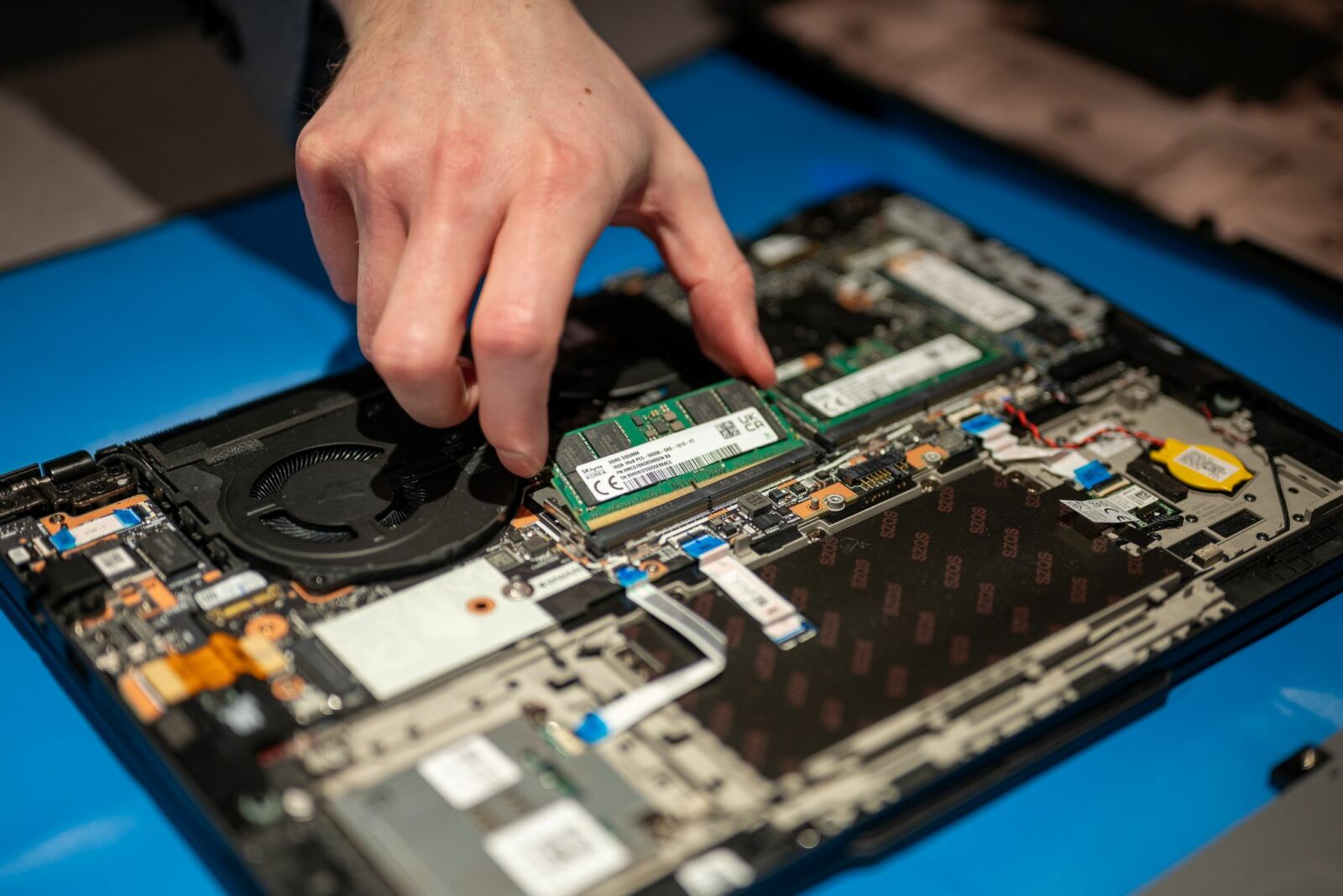 RAM being removed from a Lenovo laptop showing its motherboard and other components.